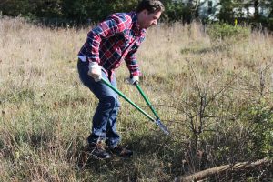 Andy Collins of Penn Hills, one of the 11 communities part of the Hilltop Alliance. The alliance is managing an urban farm project Southern Pittsburgh. Collins chops at a tree, as he volunteers his time to clear the farm. (Katy Mumaw photo)