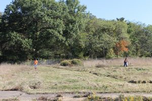 Volunteers work to mow untamed land. This was once the site of subsidized housing, and is soon to be part of a youth farm to help educate the community about horticulture and food production. (Katy Mumaw photo)